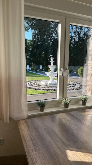 A room with a large window overlooking a garden with a fountain and potted plants. - 3,000-square-meter vacation home (12 guests) + event space (50 guests) with sauna & hot tub (Lastrup)