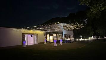 Un bâtiment doté d’un espace extérieur abrité, de plusieurs tables avec des parasols et d’une fontaine en arrière-plan.