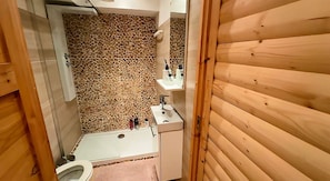 Un baño con pared de mosaicos, un lavamanos blanco y una puerta de madera.