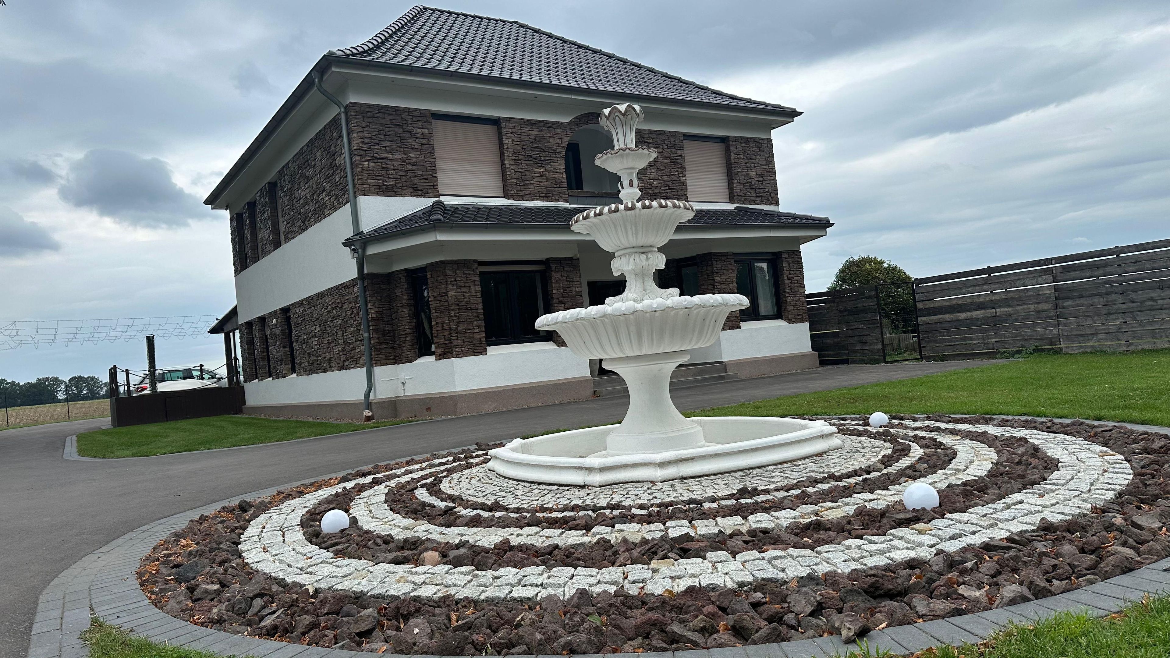 A building with a stone facade and a white fountain in the front.