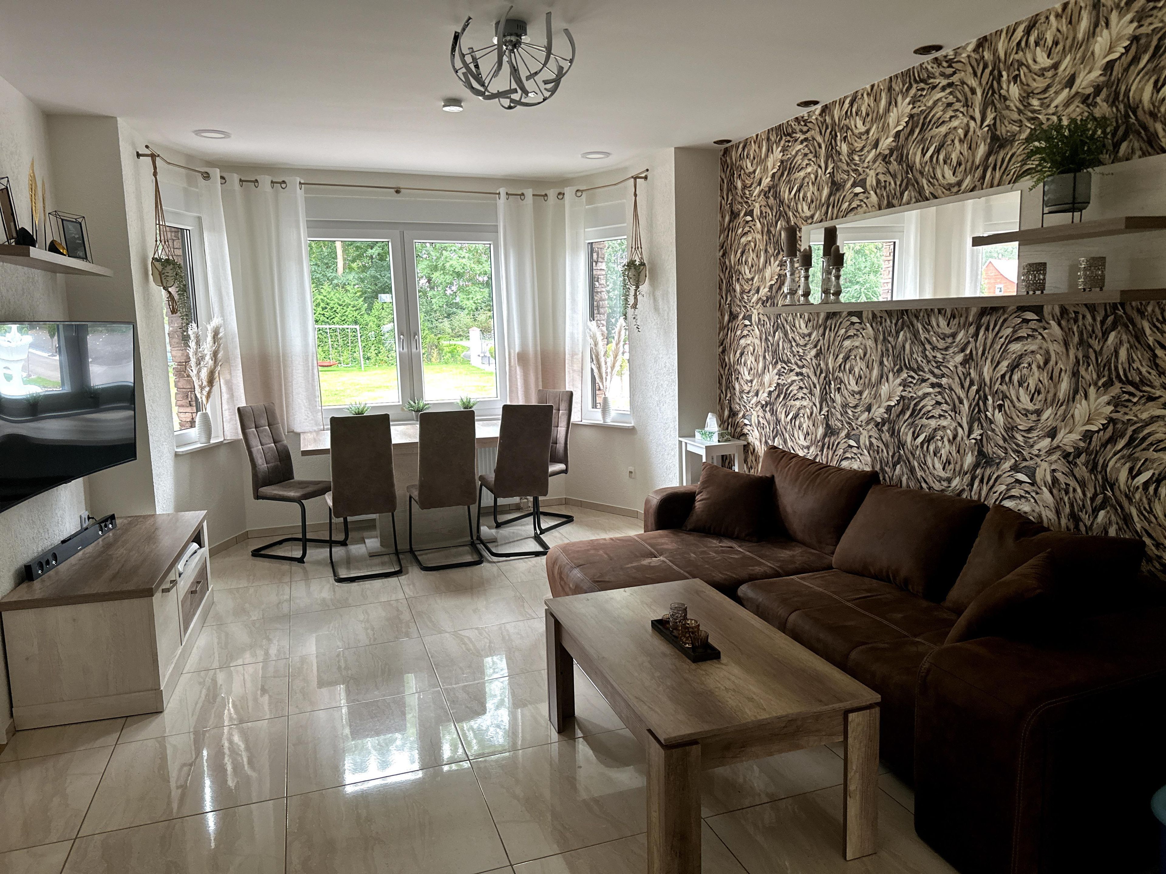 Un salon moderne comprenant un canapé, une table basse, un téléviseur et un coin repas avec des chaises et une table.
