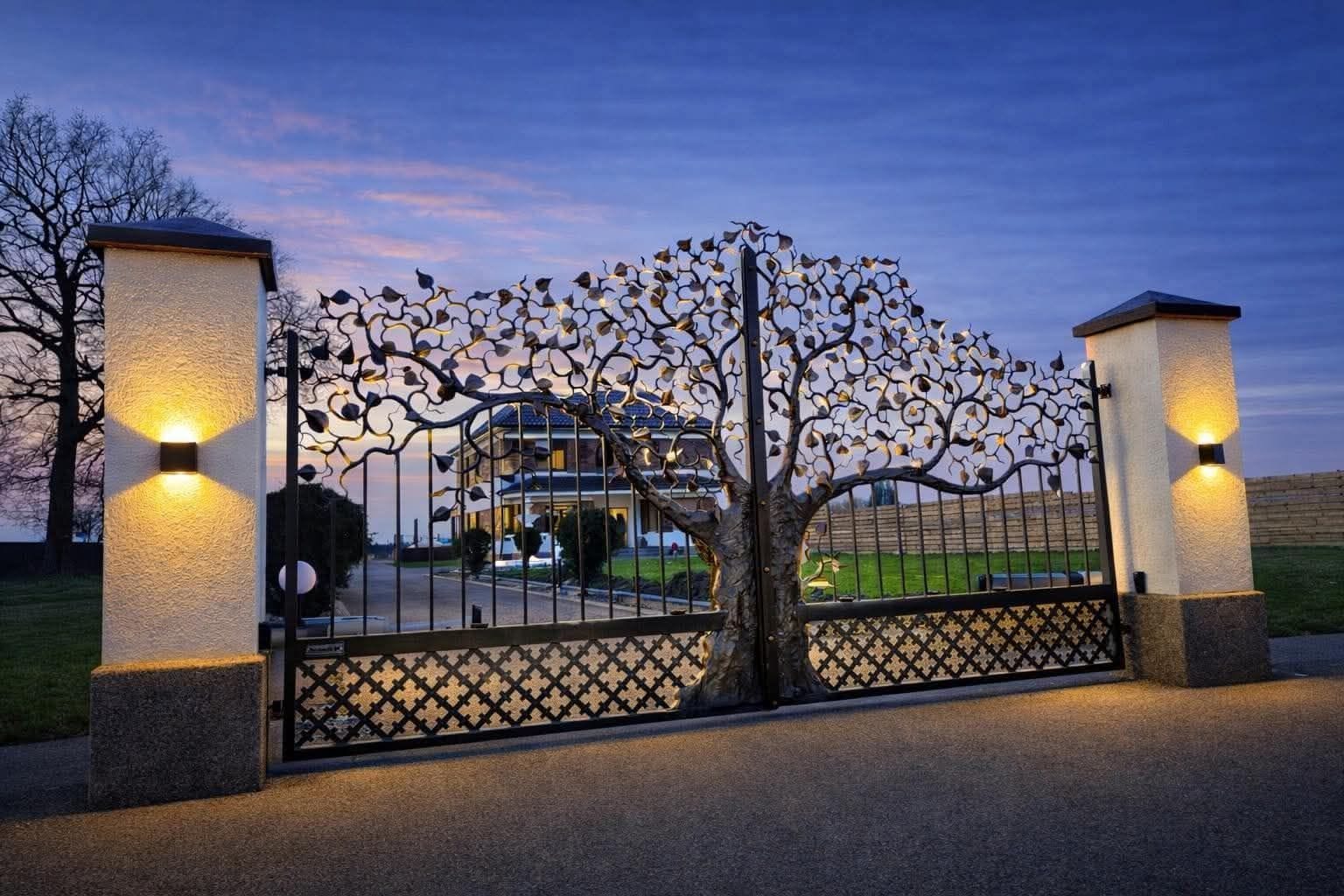A gated entrance with a decorative metal gate and two light fixtures on pillars.