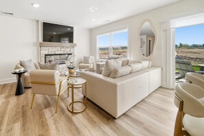A modern living room with a fireplace, a large window, and a view of the outside. - Hot Tub - Trail Access - Near Lake Michigan (South Haven)