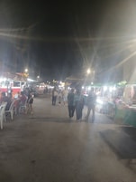Mercado noturno ao ar livre com diversos quiosques e pessoas.