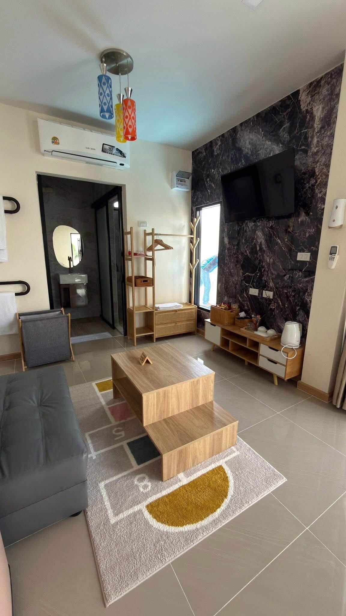 A modern living room with a grey sofa, a wooden coffee table, and a marble wall.