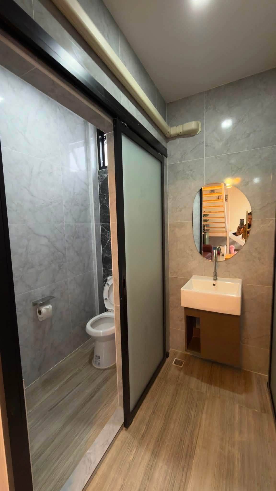 Een moderne badkamer met toilet, wastafel en spiegel.