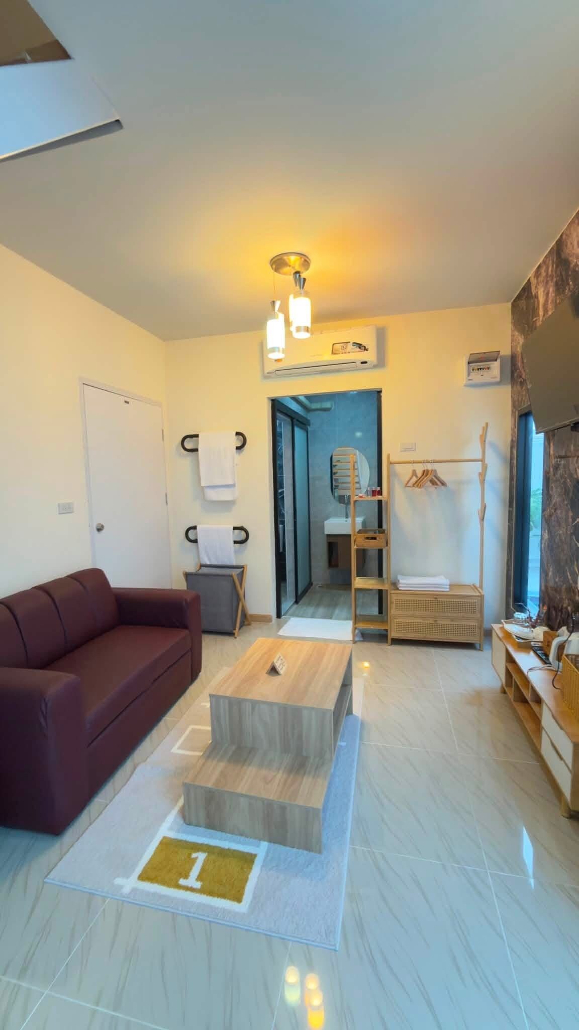 Una sala de estar moderna con un sofá, una mesa de centro y un pasillo que lleva a un baño.