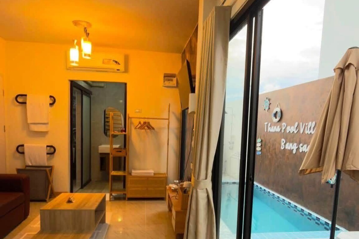 A hotel room with a large window, a pool view, a bathroom, and a seating area.