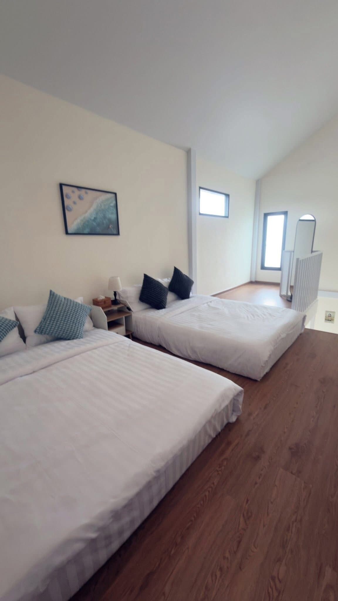 Una habitación de hotel con dos camas, una mesita de noche, una lámpara, un cuadro y un radiador.