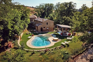Ein Haus mit Swimmingpool, umgeben von einem gepflegten Rasen und Bäumen.