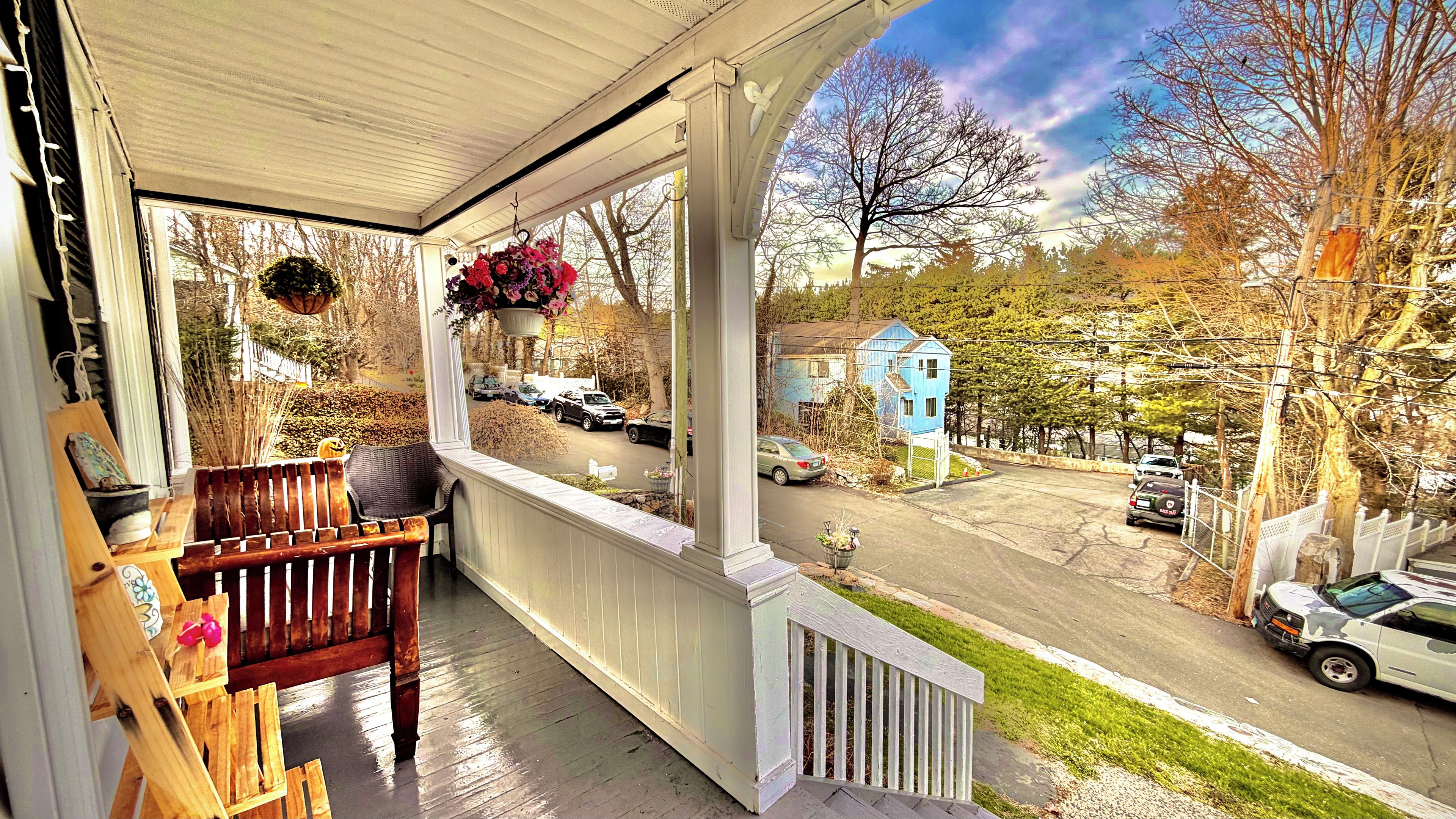A porch with a wooden bench and a hanging flower basket.