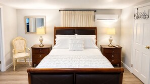 Ein ordentlich eingerichtetes Schlafzimmer mit einem großen Bett, zwei Nachttischen inklusive Lampen, einem Sessel und einem Spiegel.
