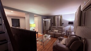 Ein modernes Wohnzimmer mit einem Glastisch, einer Ledersofa und einem großen Spiegel.