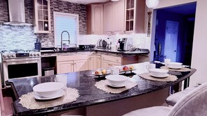Una cocina con encimera negra, armarios blancos y una estufa.