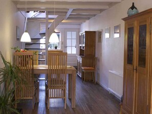 A dining area with a wooden table and chairs, a staircase, and a cabinet with glass doors. - Het Bakkerijtje (Oudeschild)