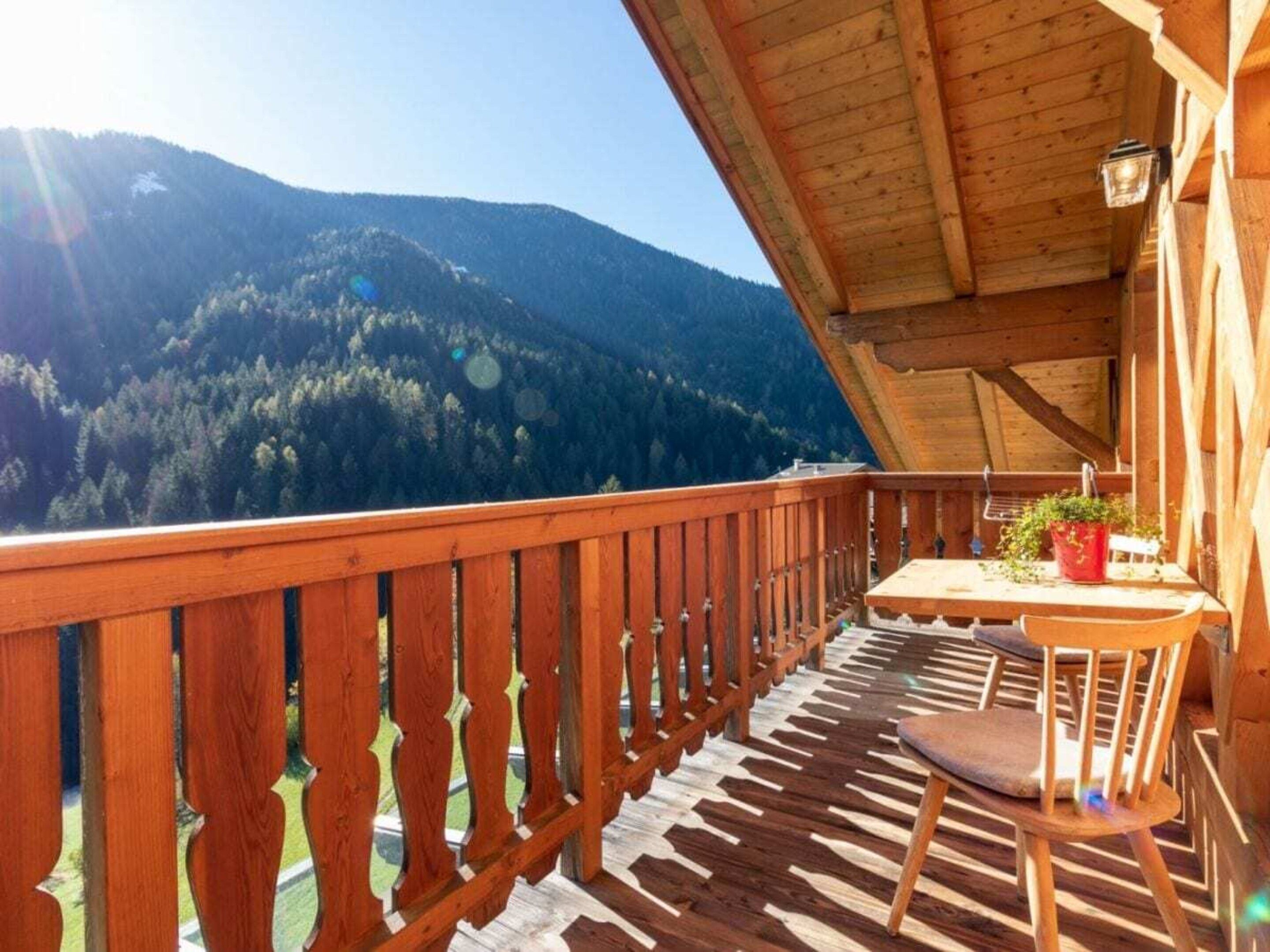 A wooden balcony with a view of a forested mountain.