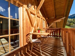 Eine Holzterrasse mit Tisch und Stühlen mit Blick auf eine gebirgige Landschaft.