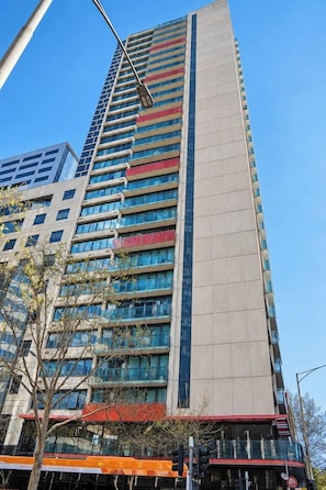 A tall building with multiple floors, large windows, and a prominent vertical strip of red and beige. - CBD Studio by Vic Market | Gym, Wi-Fi & Free Tram (Melbourne)