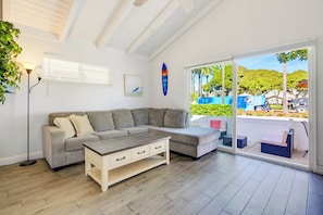 A modern living room with a sectional sofa, a coffee table, and a large sliding glass door leading to an outdoor area. - Short Walk To Sand Prefect For Families, Lrg Patio (Newport Beach)