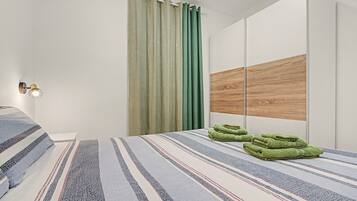 A modern bedroom with a bed, a wall-mounted light, a curtain, and a wooden panel.