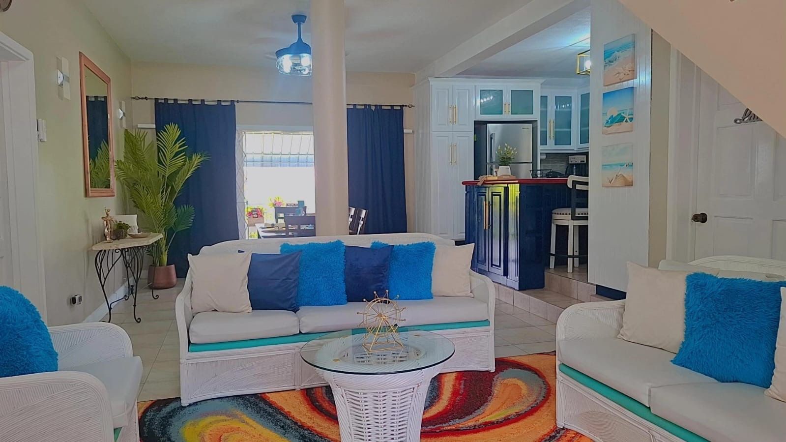 A living room with a sofa, armchairs, a coffee table, and a kitchen in the background.