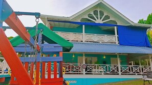 A two-story building with a balcony and a play structure in the foreground. - Beautiful Villa Views (Tobago)