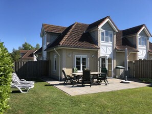 A residential house with a patio, a lawn, and a wooden fence. - Duinpan 22 Right by the sea (Kamperland)