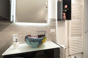 Een badkamer met een grote, kleurrijke wasbak, een wit toilet en een handdoekhouder.