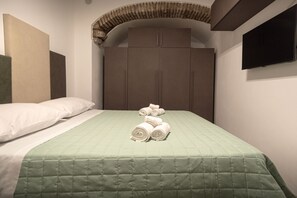 Een hotelkamer met een bed, een kledingkast en een televisie aan de muur.