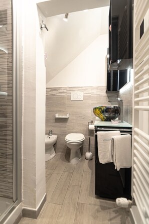 Uma casa de banho moderna com chuveiro, sanita, bidé e lavatório com porta-toalhas.