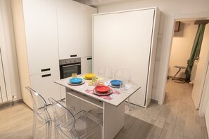 A modern kitchen with a dining table set for four, featuring clear chairs and a variety of colorful plates. - One Bedroom apartment in the centre of Assisi (Assisi)