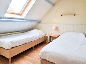 A room with two beds, a small table, a lamp, and a sloped ceiling with skylights. - Do02 Holiday Home Novawe (Domburg)