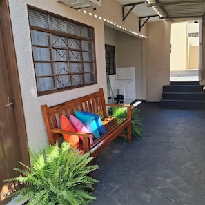 A wooden bench with colorful cushions, a window with a grid pattern, and a staircase leading to an upper level. - CASA 1111 FUNDO (São José do Rio Preto)