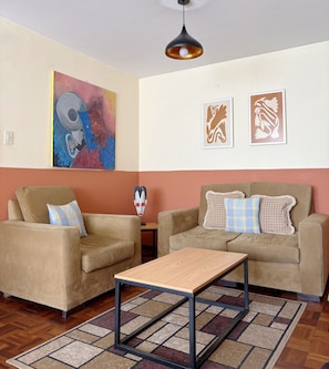 Una sala de estar con dos sofás, una mesa de centro y un cuadro en la pared.