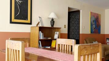 A dining area with a wooden table and chairs, a lamp, and artwork on the walls.