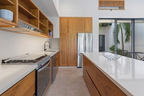 A modern kitchen with wooden cabinets, a stainless steel refrigerator, and a glass door leading to a balcony. - Modern home overlooking golf course with private pool - minutes to the beach (Tangolunda)