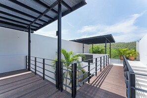 A covered outdoor area with a wooden deck, metal railings, and potted plants. - Modern home overlooking golf course with private pool - minutes to the beach (Tangolunda)
