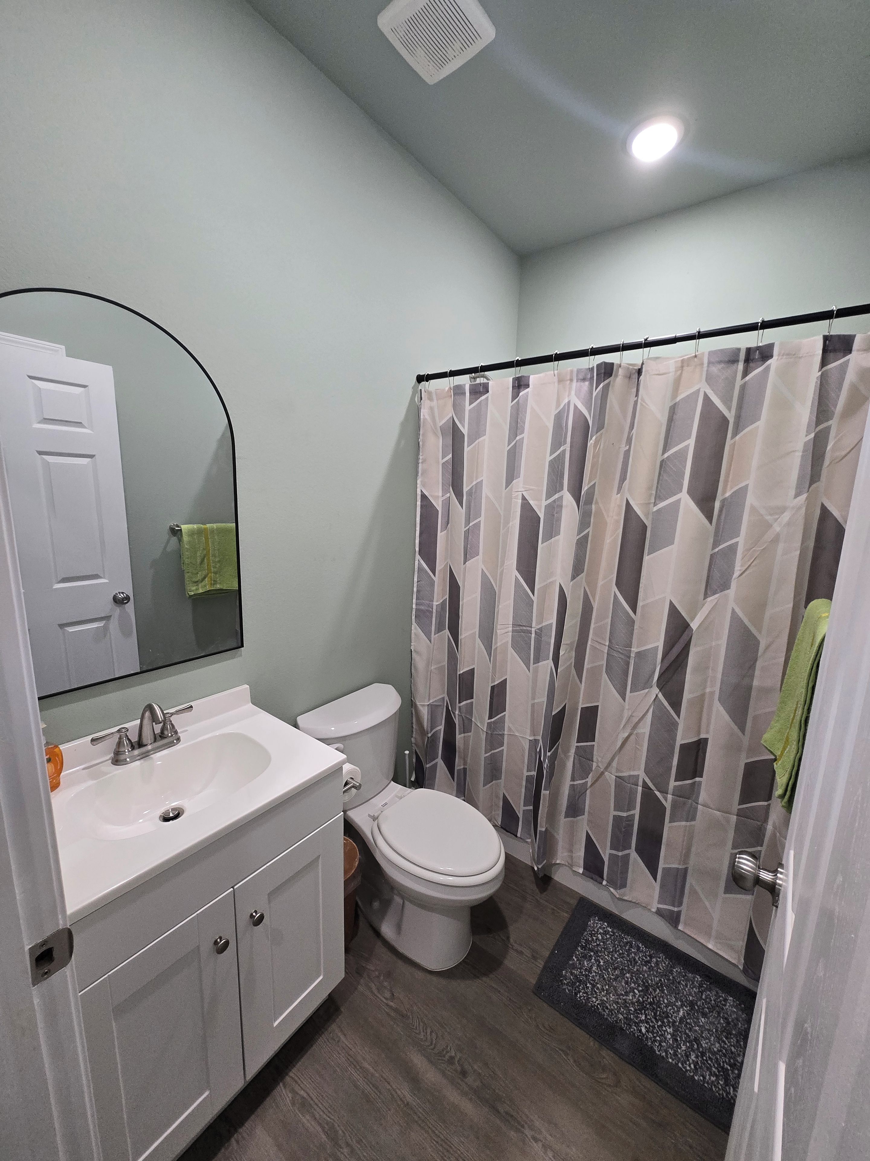 A bathroom with a white sink, a toilet, and a shower curtain with a geometric pattern.