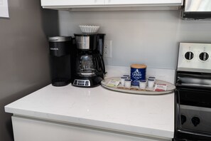 Eine Küche mit einer Kaffeemaschine, einer Waage und Kaffeekapseln auf der Arbeitsplatte.