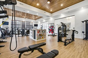 Ein Fitnessraum mit unterschiedlichen Trainingsgeräten, einer Bank und einem Zeitschriftenständer.