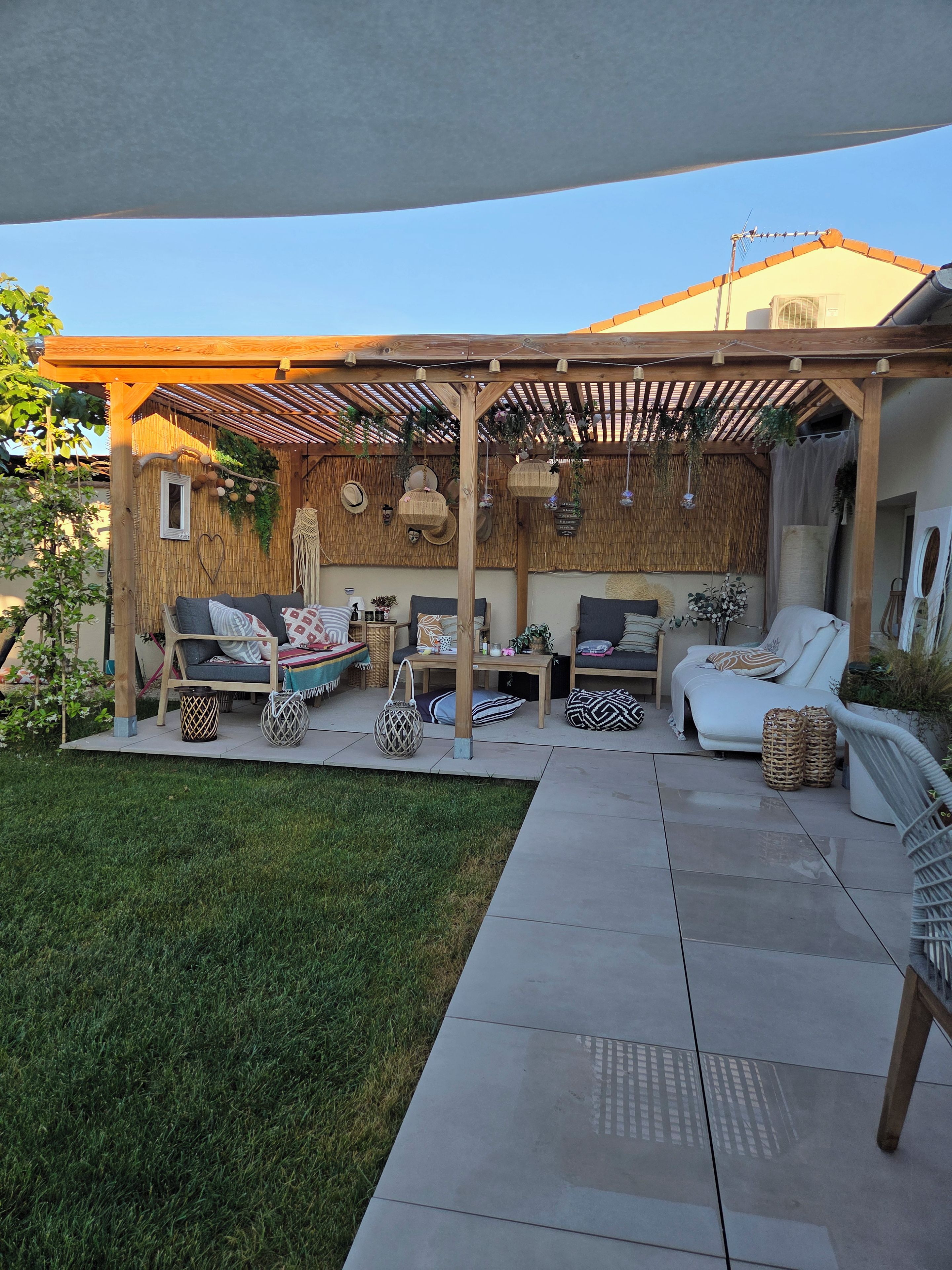 A covered outdoor seating area with a pergola, cushioned seating, and decorative elements.