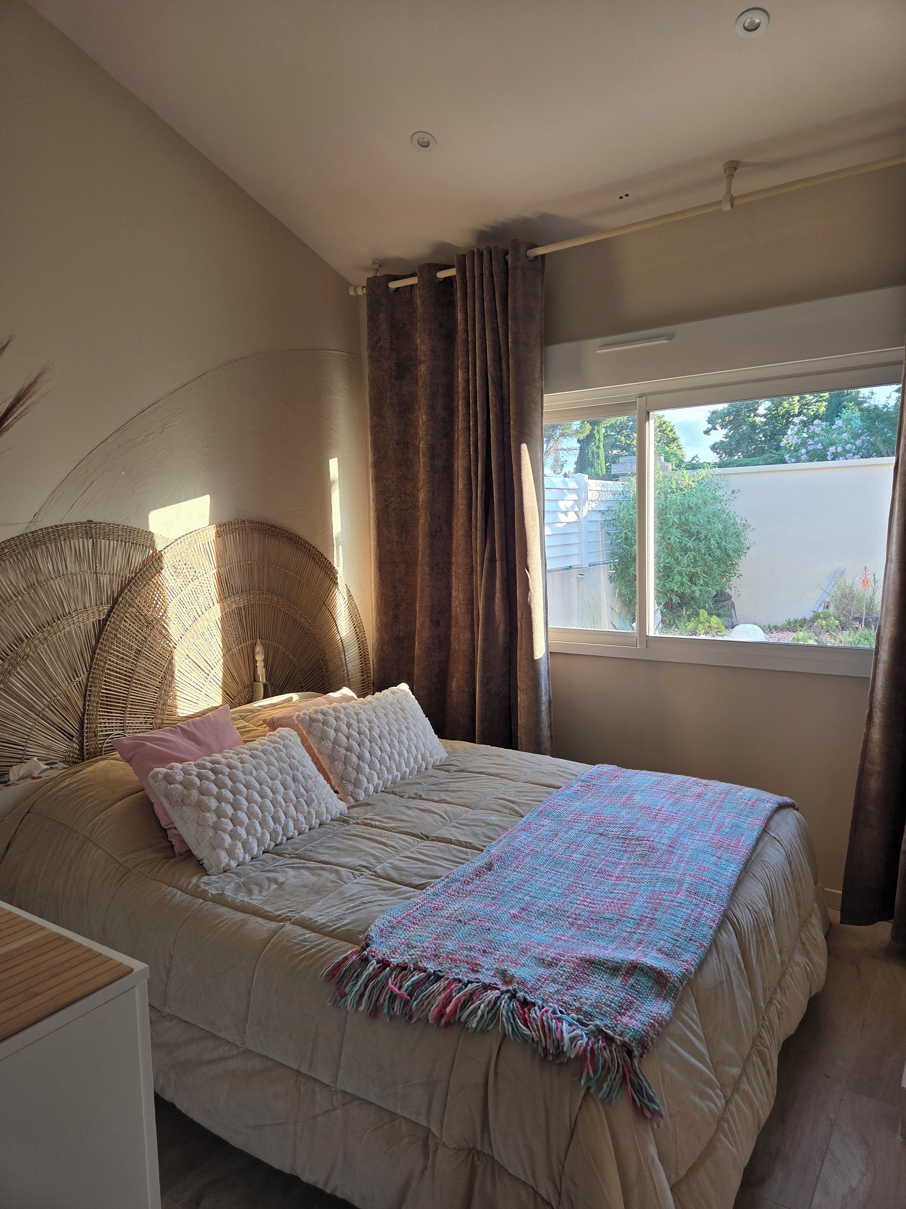 A bedroom with a bed, a window, curtains, and a ceiling fan.