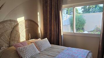 A bedroom with a bed, a window, curtains, and a ceiling fan.