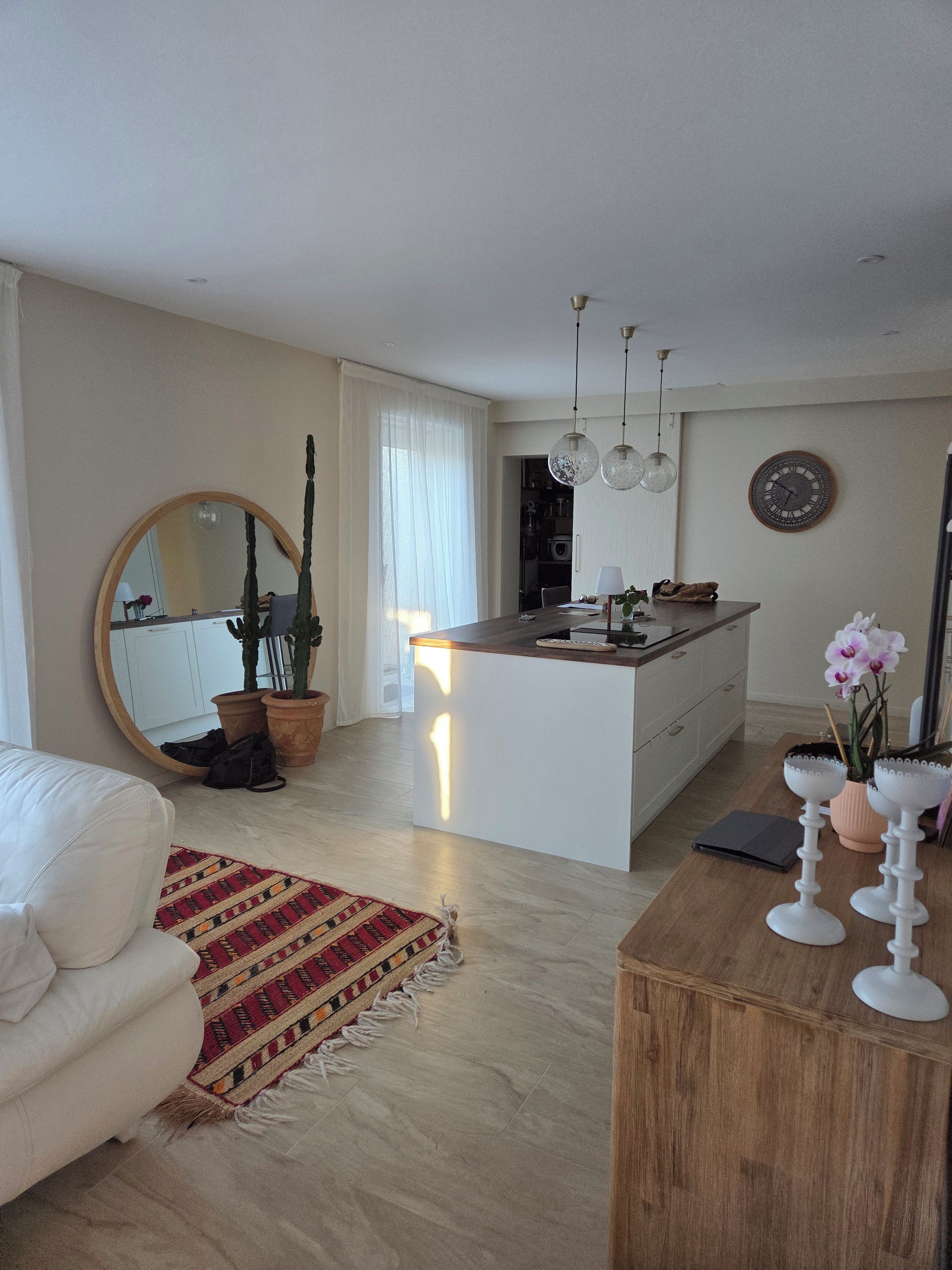 A modern living room with a white sofa, a wooden coffee table, and a kitchen area with a central island.