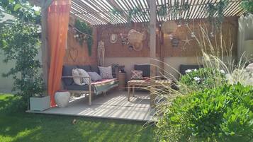 A covered outdoor seating area with a sofa, chairs, and a table.