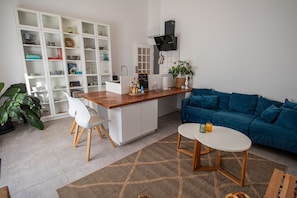 A modern kitchen with white cabinetry, a wooden island, and a blue sofa. - Farm Lodges Olive, Casa Jacaranda, Moncarapacho Countryside (Moncarapacho)
