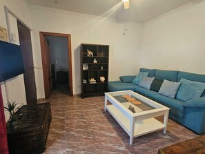 A living room with a blue sofa, a white coffee table, and a dark wooden bookshelf.