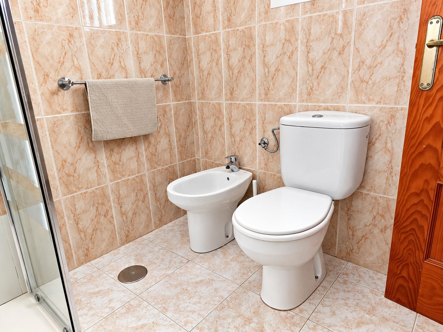 Een badkamer met toilet, bidet en een handdoekhouder.