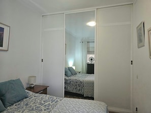 Una camera da letto con un letto, un comodino, uno specchio e un armadio.