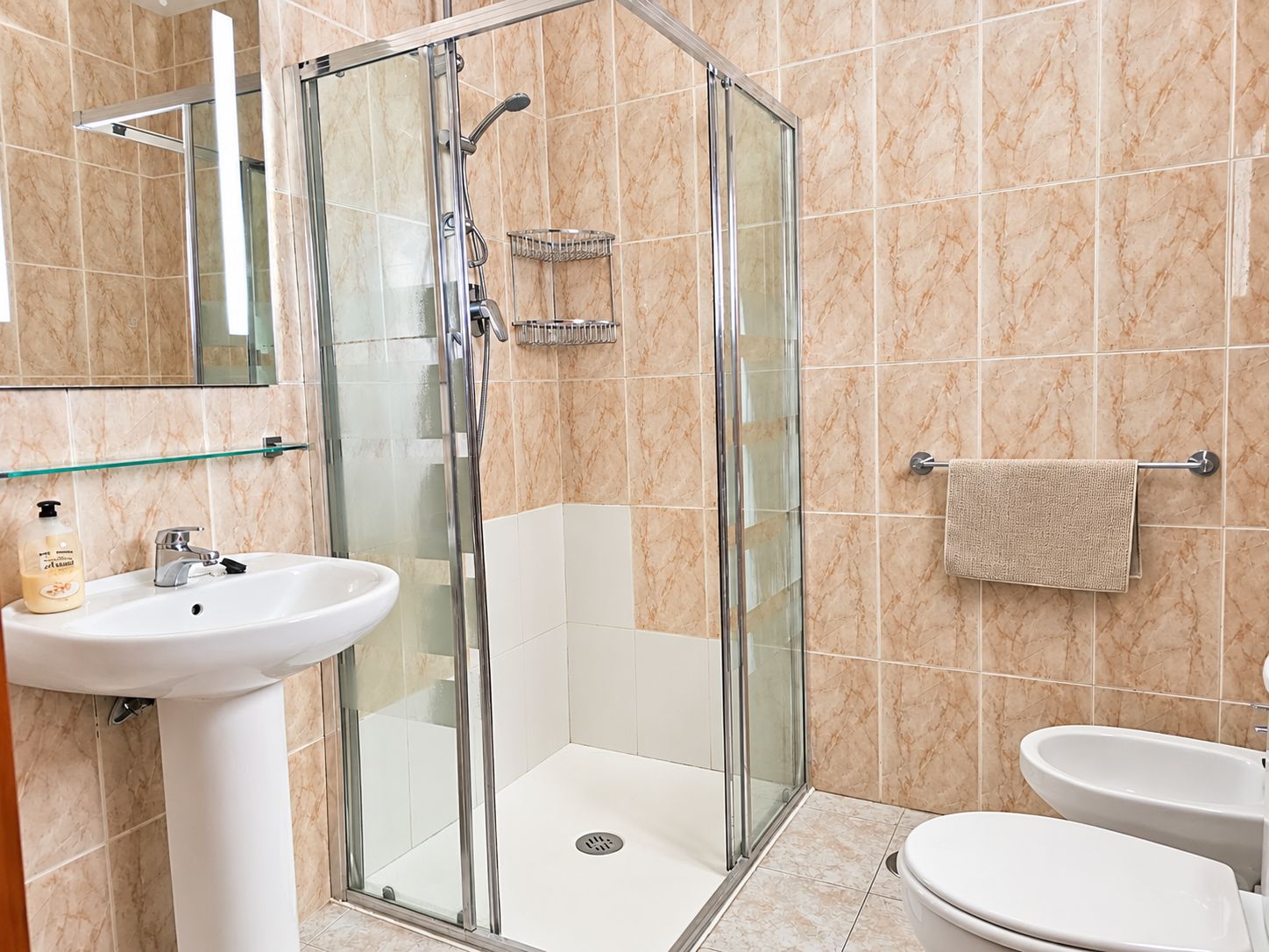 Een moderne badkamer met een douche met glazen wand, een wastafel en een toilet.